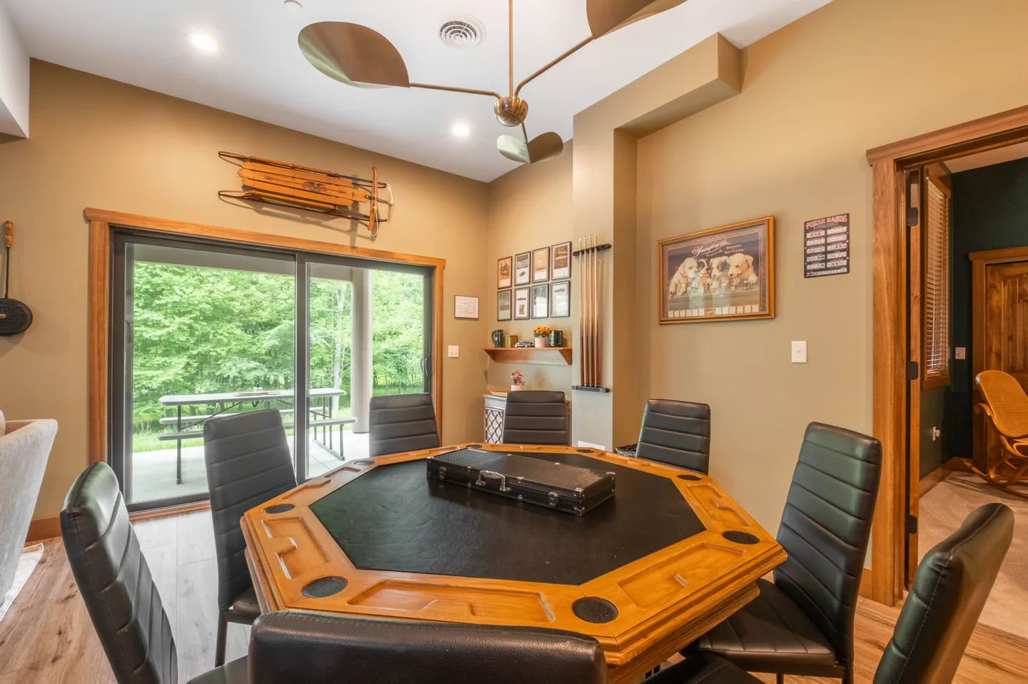 Game room featuring an octagonal poker table with black chairs, surrounded by sliding glass doors leading to a patio.