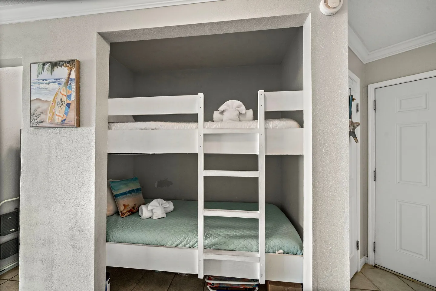 Built-in white bunk beds recessed into a hallway wall alcove.