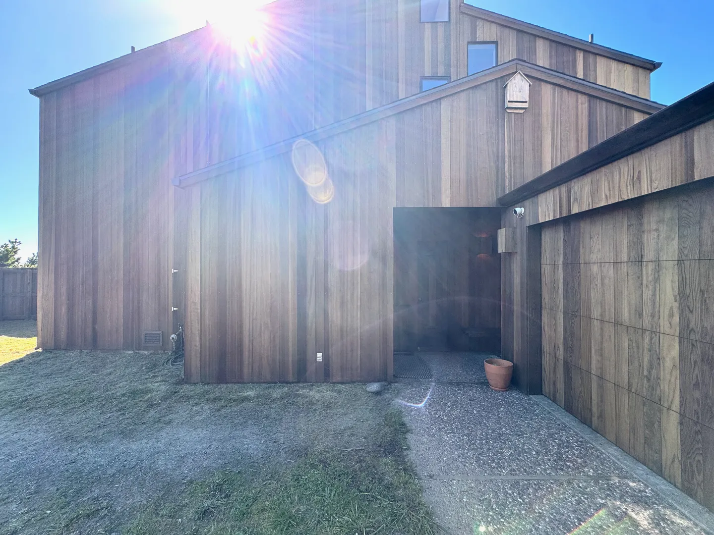 Exterior view of a multi-story home with vertical wood siding and a covered entry alcove.