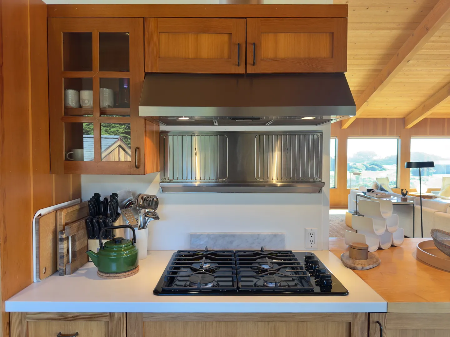 Kitchen counter area with a built-in gas cooktop, stainless steel range hood, and warm wood cabinetry.