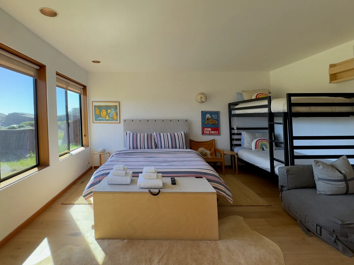 Bedroom with a queen-sized bed, bunk beds, a storage bench, and large picture windows.