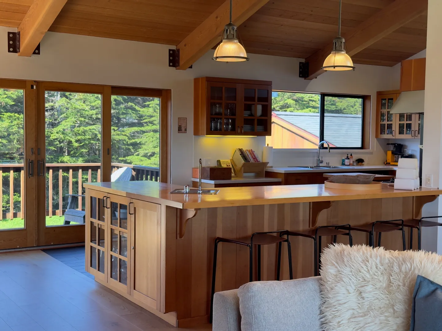 Open-concept kitchen with wood island, bar seating, exposed ceiling beams, and sliding glass doors leading to an outdoor deck.