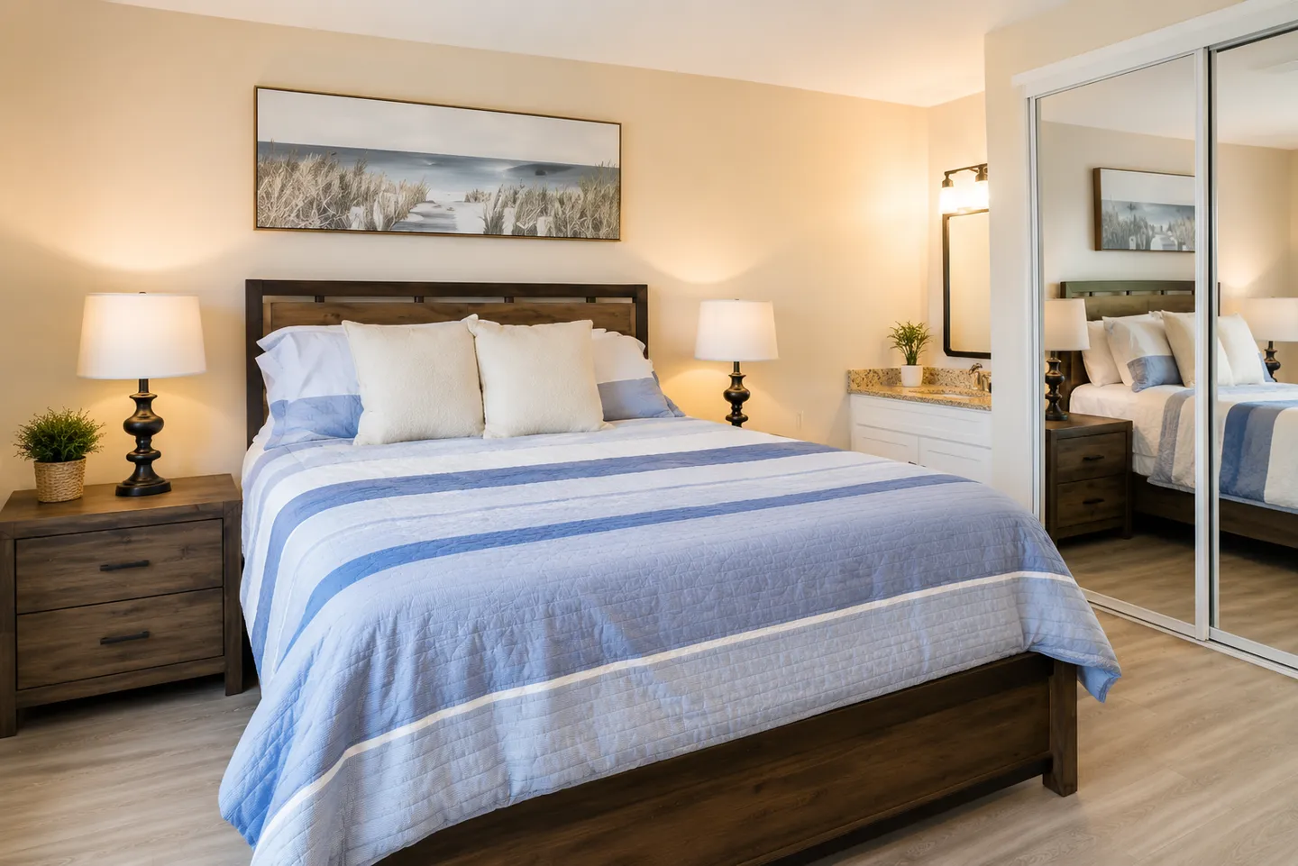 Bedroom with a wooden bed, blue and white striped bedding, matching nightstands with lamps, and mirrored closet doors.