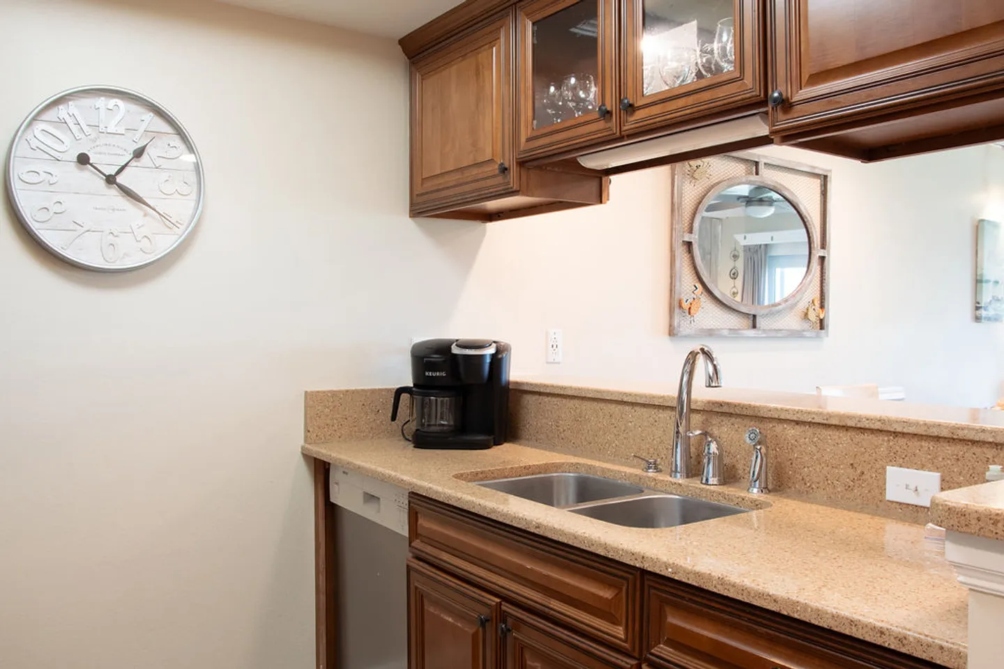 Kitchen counter with a double-basin sink, wooden cabinetry, and a coffee maker.