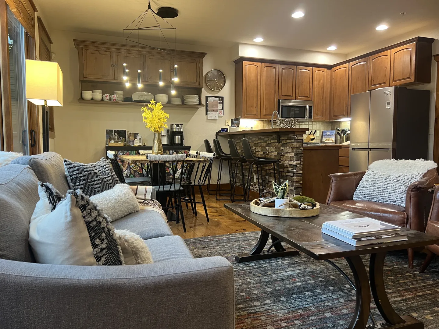Open-concept living room, dining area, and kitchen with wood cabinets, breakfast bar, and comfortable seating.