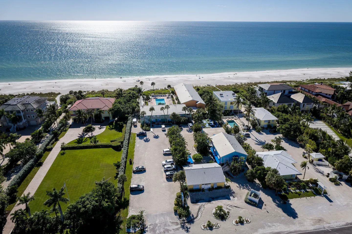Aerial view of a coastal resort complex adjacent to a sandy beach and the ocean on a clear, sunny day.