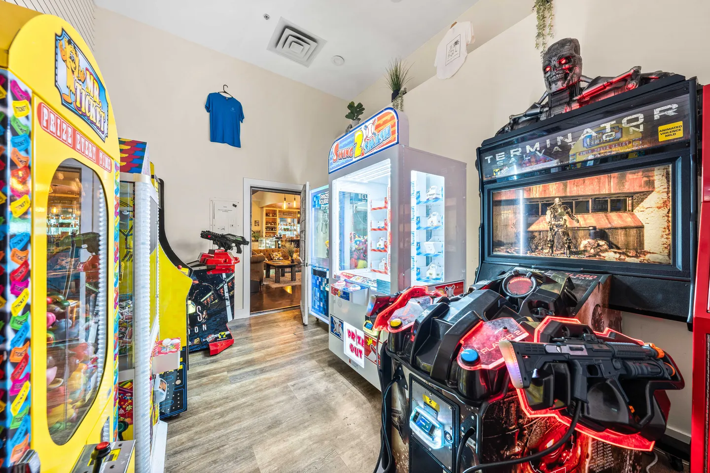 Game room filled with classic arcade and claw machines along wood-look flooring.