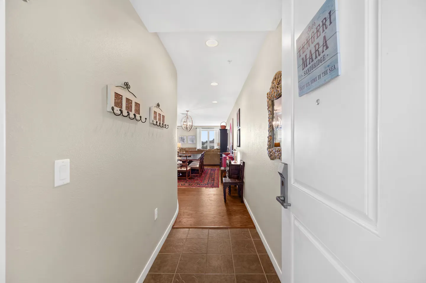 Entryway with tile flooring leading down a hallway toward a brightly lit open-concept living and dining area.