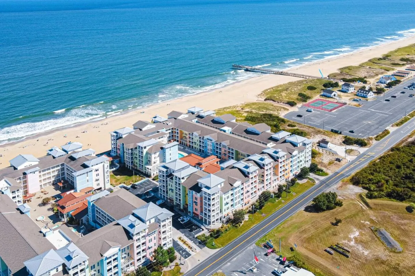 Aerial view of a colorful beachfront resort complex situated along a sandy beach and blue ocean waters.
