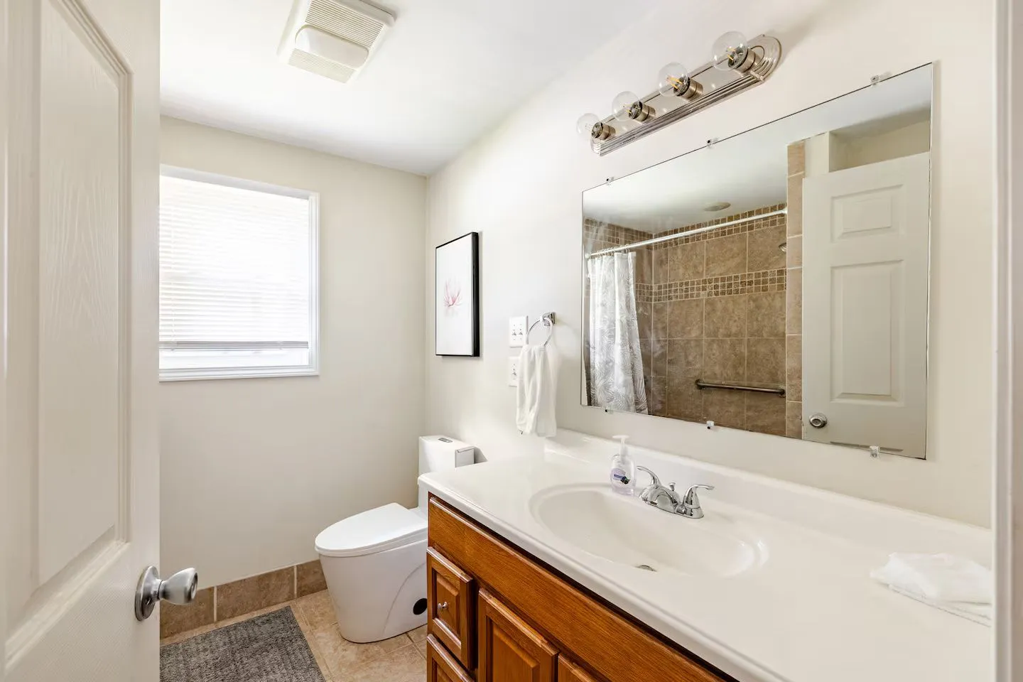 Bathroom featuring a wood vanity with a white countertop, mirror, modern toilet, and a window with blinds.