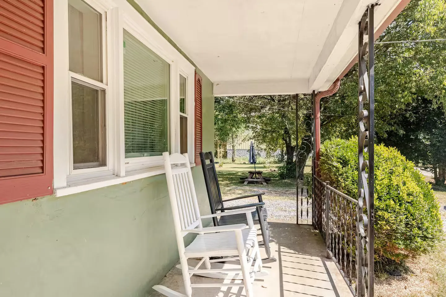 Front porch with two rocking chairs overlooking a green yard and trees.