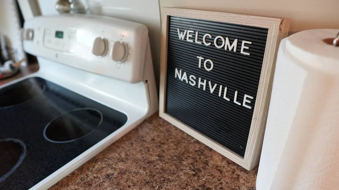 Close-up of a kitchen countertop with a letter board reading 'WELCOME TO NASHVILLE' next to a white stove.