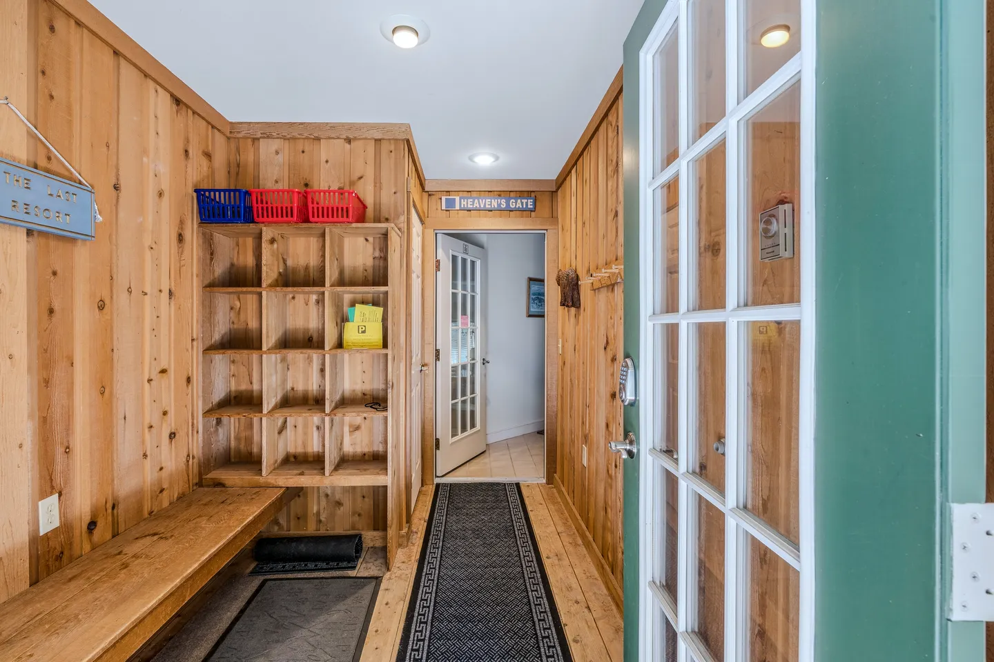 Entryway mudroom with wood-paneled walls, built-in cubbies, a bench, and a runner leading to an inner doorway.