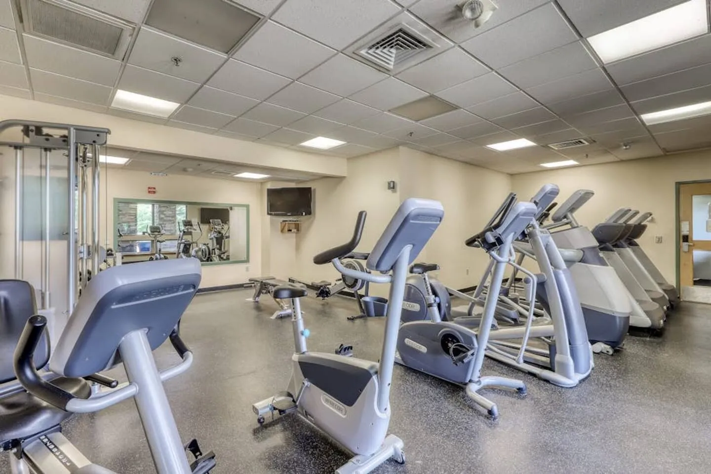 Indoor fitness center featuring stationary bikes, elliptical machines, and strength training equipment.