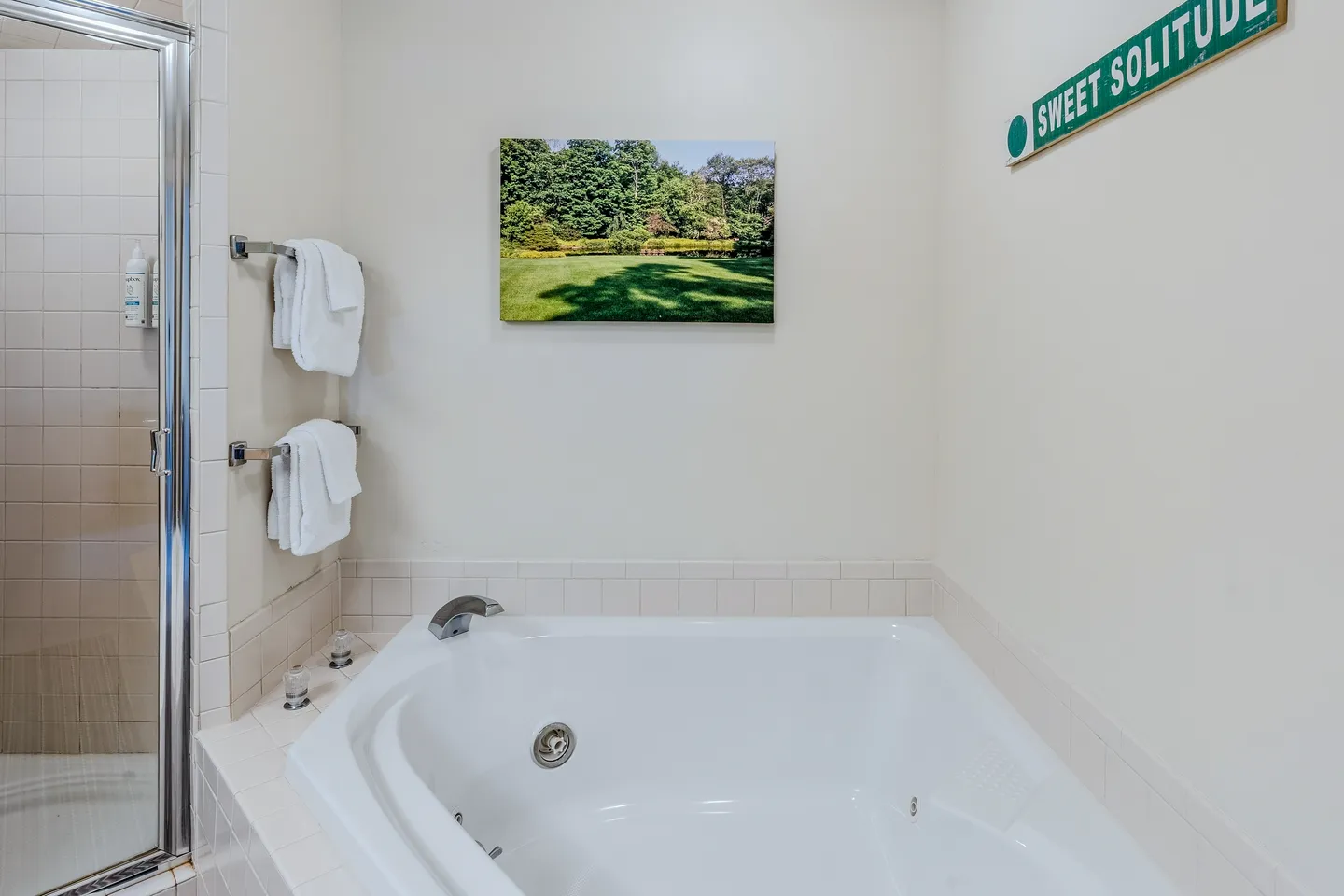 A corner jetted bathtub next to a glass-door walk-in shower in a bathroom with white walls.