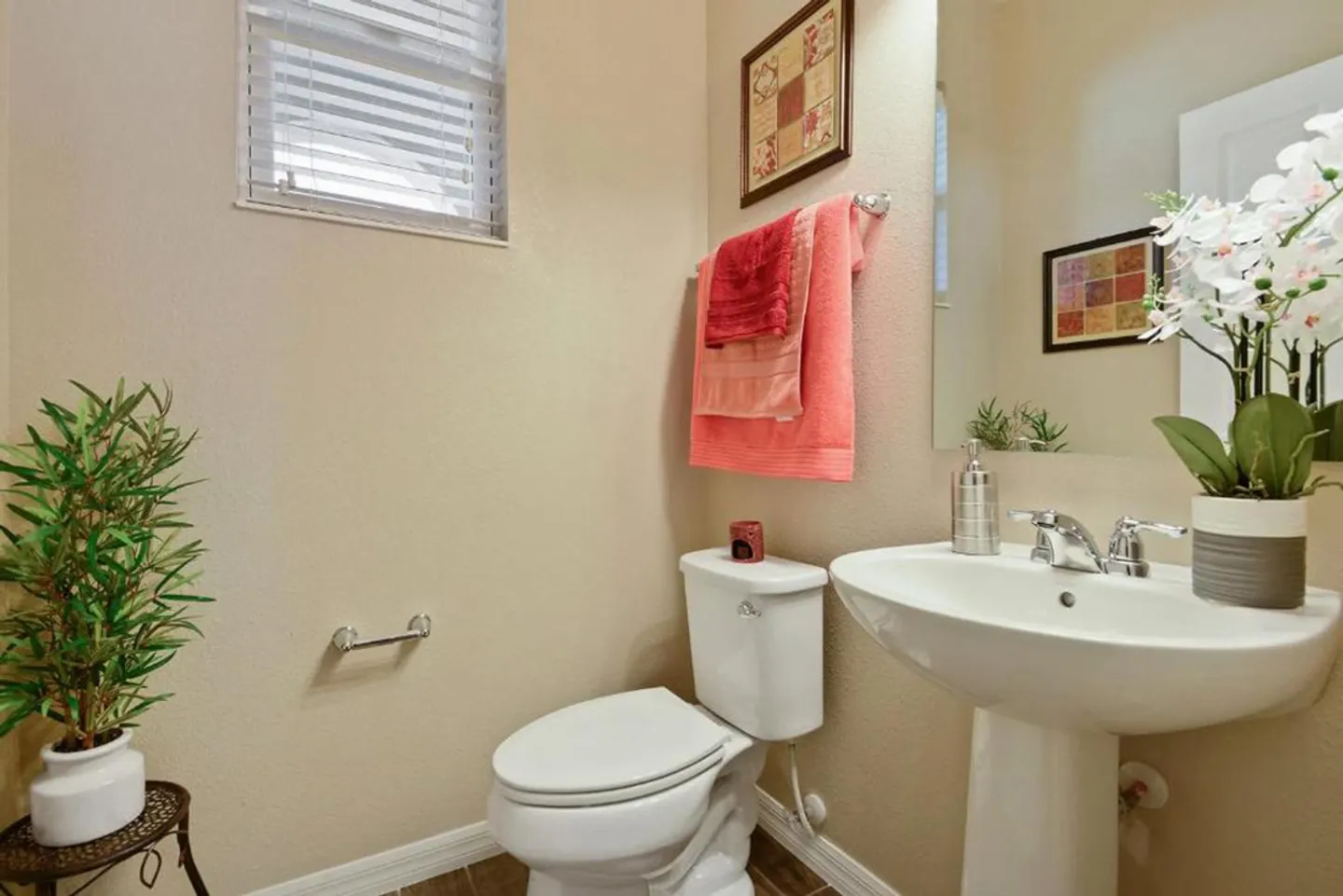 Half bathroom featuring a white toilet, pedestal sink, wall mirror, and window with blinds.