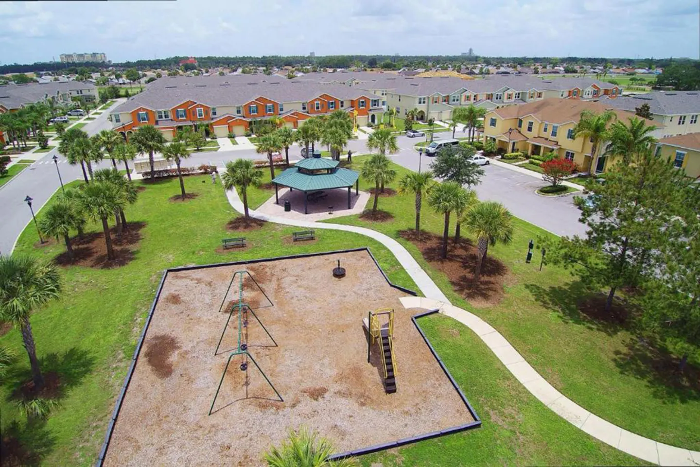 Aerial view of a community park featuring a playground, gazebo, paved walkway, and surrounding townhomes.