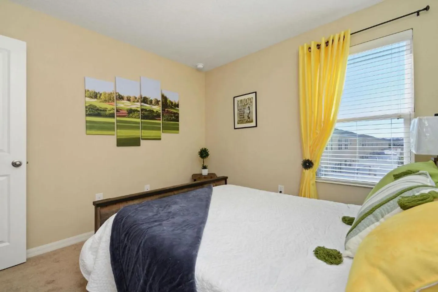 Bedroom with a wooden bed frame, beige walls, golf-themed wall art, and a window with yellow curtains.