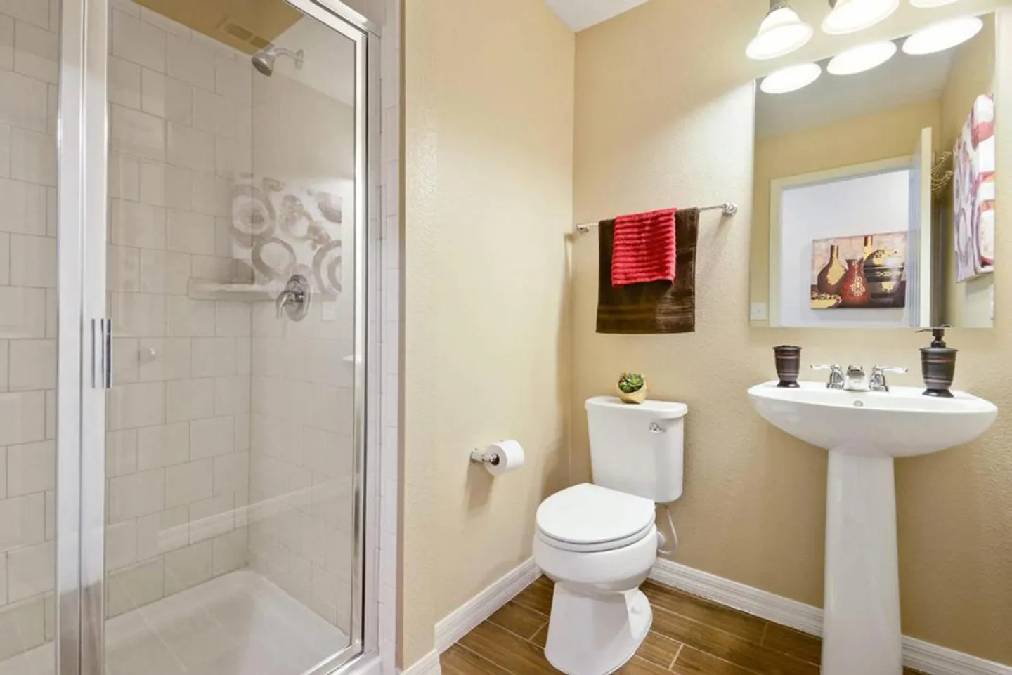 Bathroom with a glass-enclosed walk-in shower, pedestal sink, and toilet.