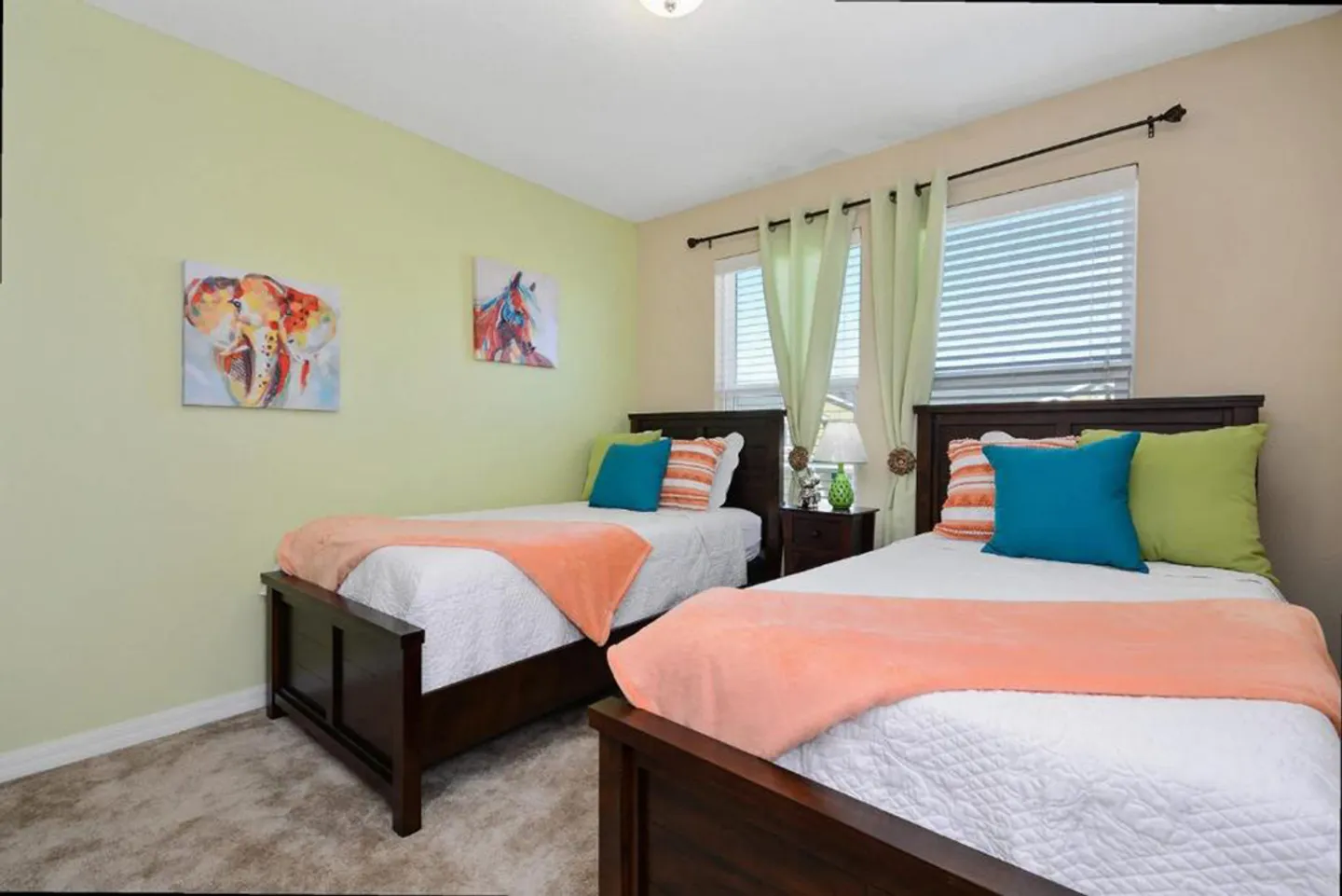 Bedroom featuring two dark wood twin beds dressed in white quilts with peach, blue, and lime accent pillows.