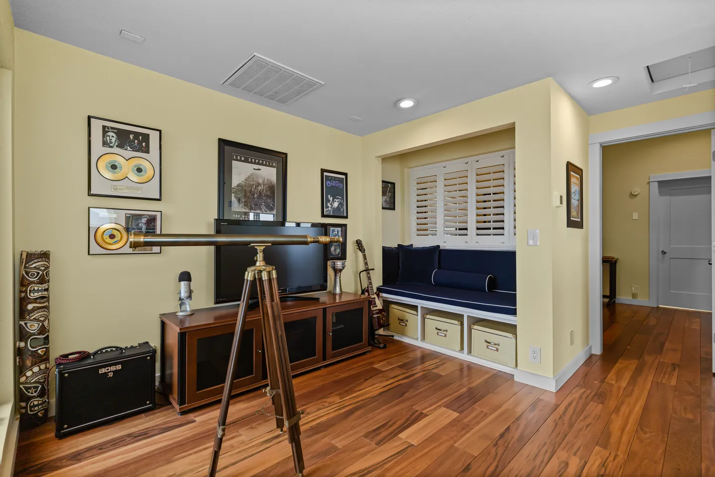 An entertainment nook with wood-style flooring, a TV console, decorative telescope, and a built-in window daybed.