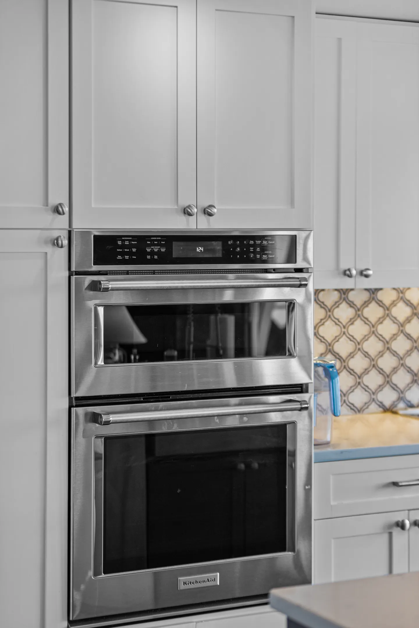 Close-up view of built-in stainless steel double wall ovens surrounded by white kitchen cabinetry.