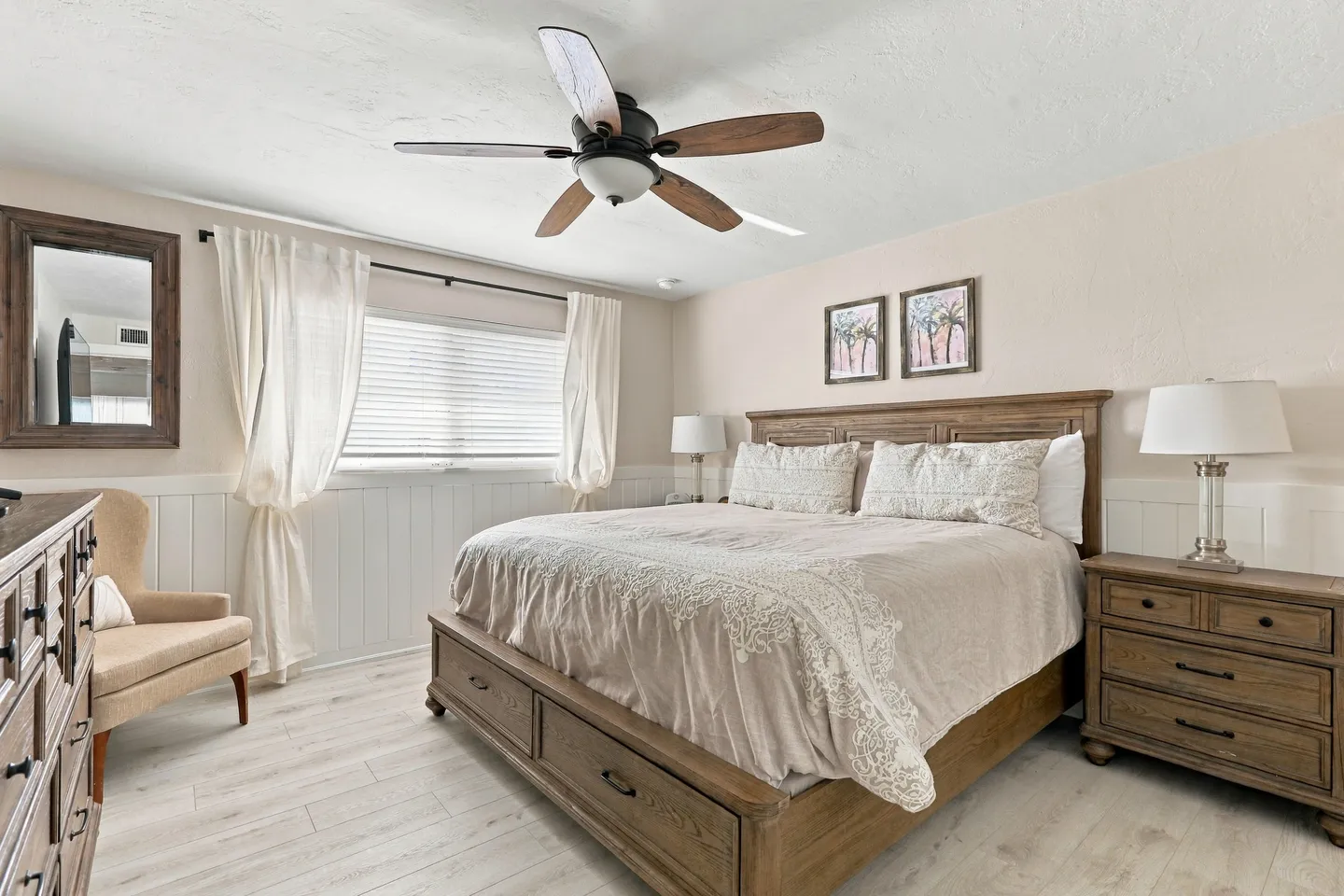 Bedroom featuring a wooden bed with built-in drawers, matching nightstands, light wood-look flooring, and a ceiling fan.