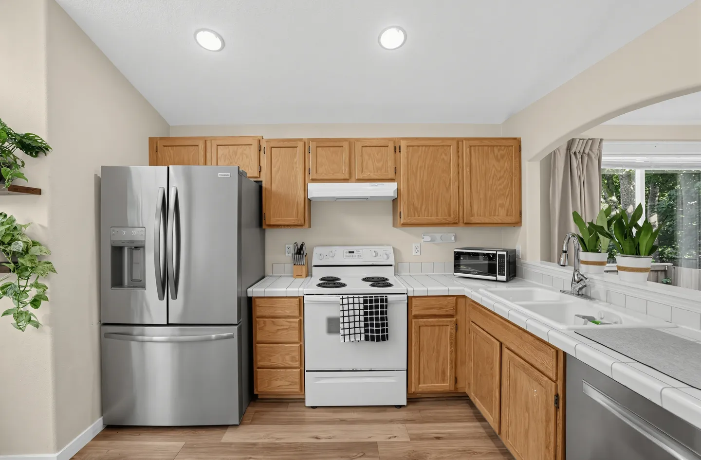 Kitchen featuring light wood cabinets, white tile countertops, an electric range, stainless steel French door refrigerator, and a double-basin sink.