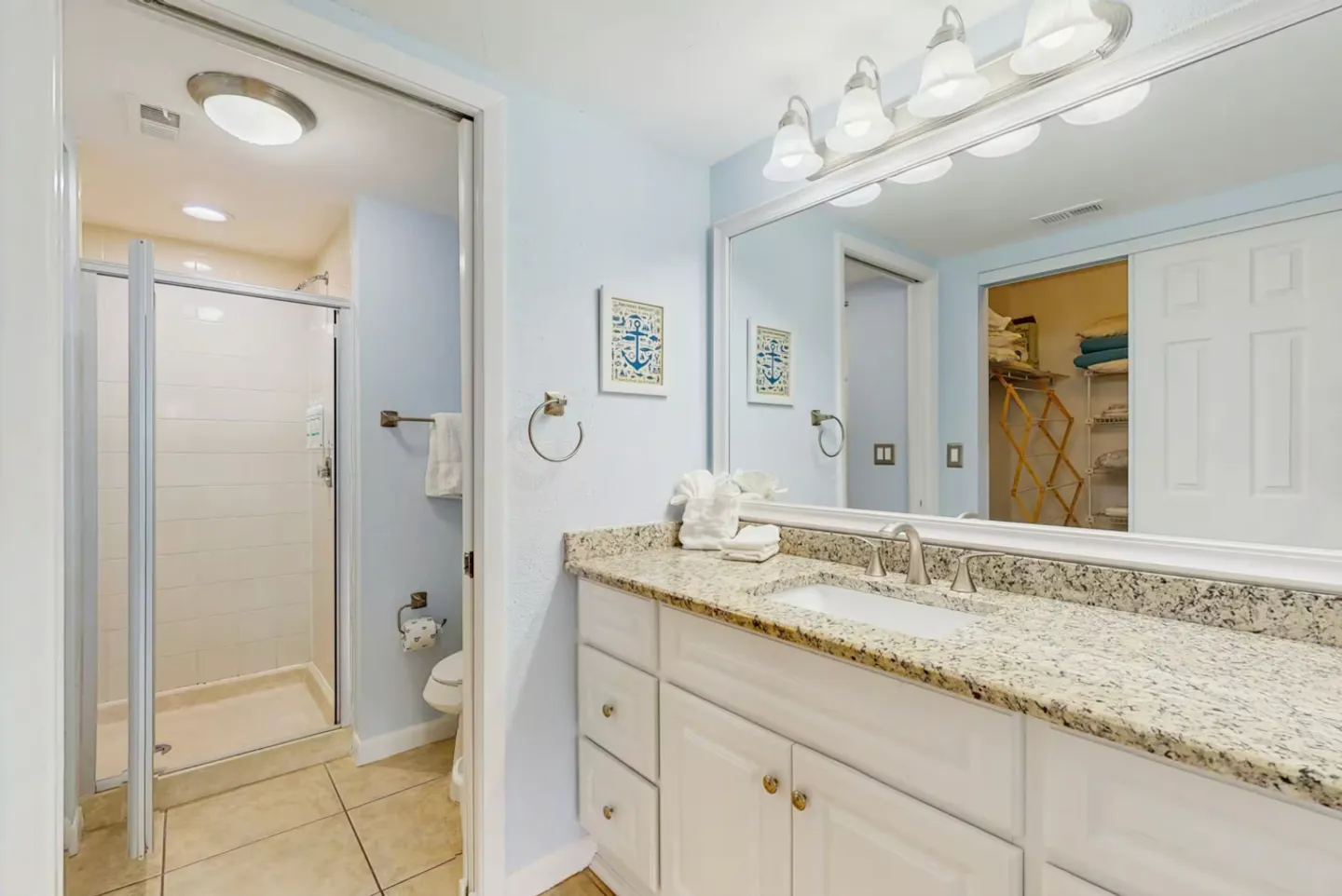 Bathroom featuring a white vanity with granite-style countertop and a walk-in shower in an adjacent area.