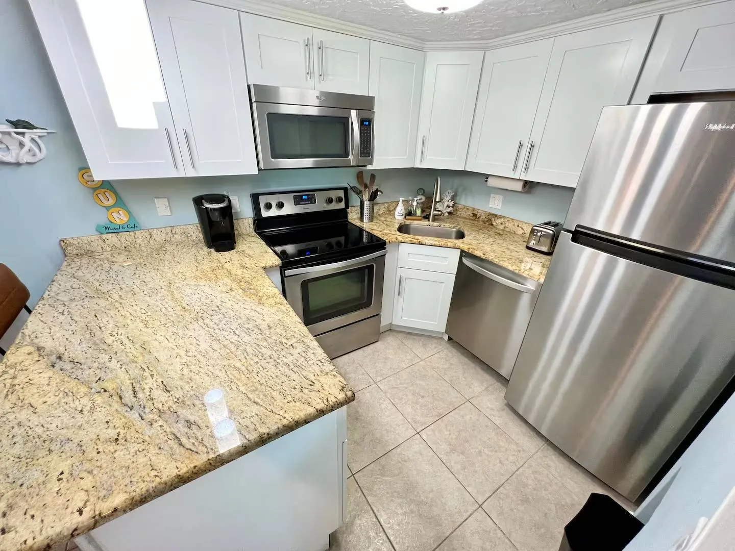 Kitchen with white cabinetry, patterned granite-look countertops, and stainless steel appliances.