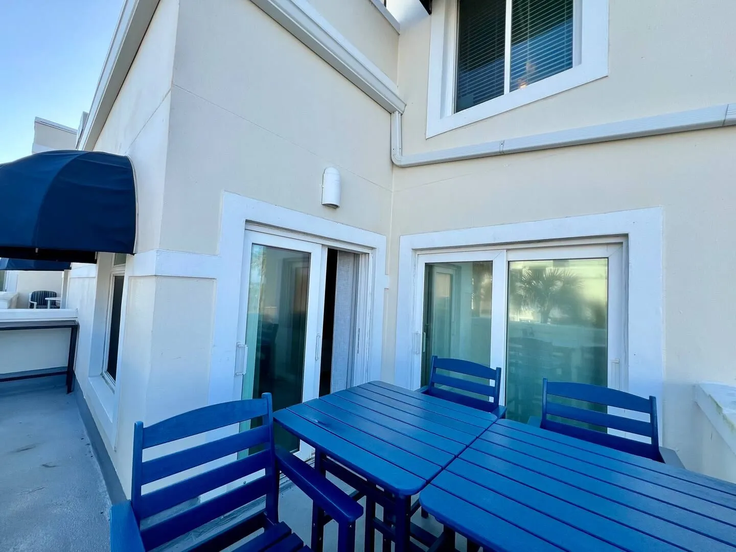Balcony or patio area featuring blue outdoor dining furniture next to sliding glass doors.