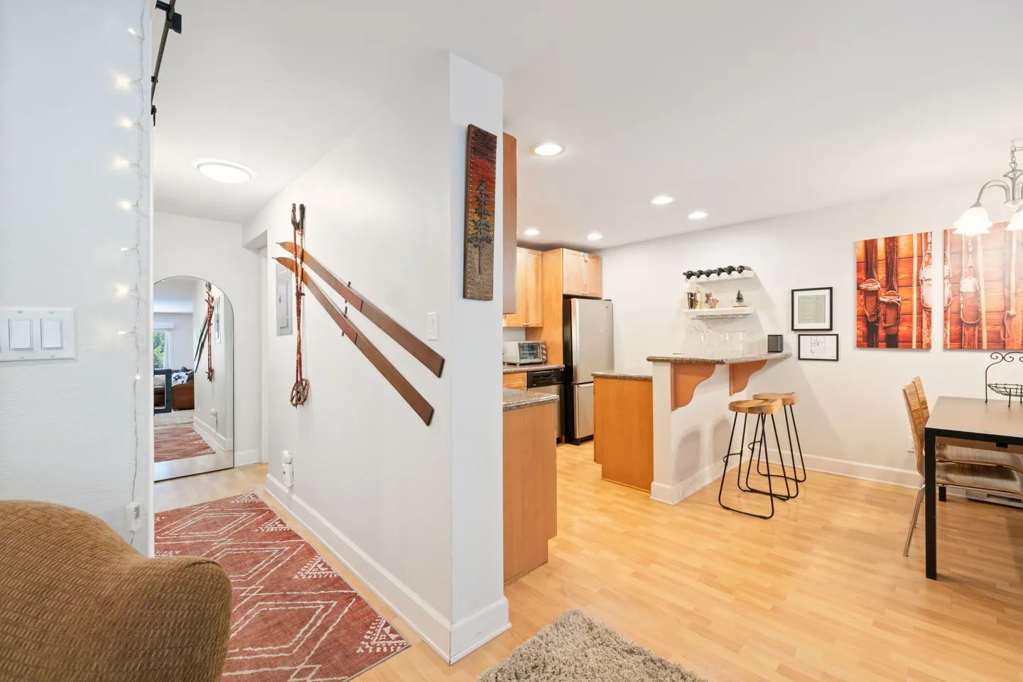 Hallway and open kitchen with a breakfast bar, wooden cabinetry, and dining area.