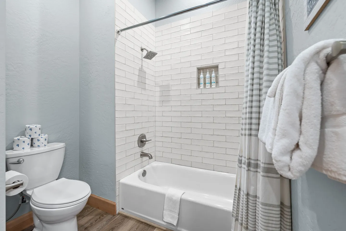 Bathroom showing a white toilet, bathtub-shower combination with white subway tile, and folded white towels.