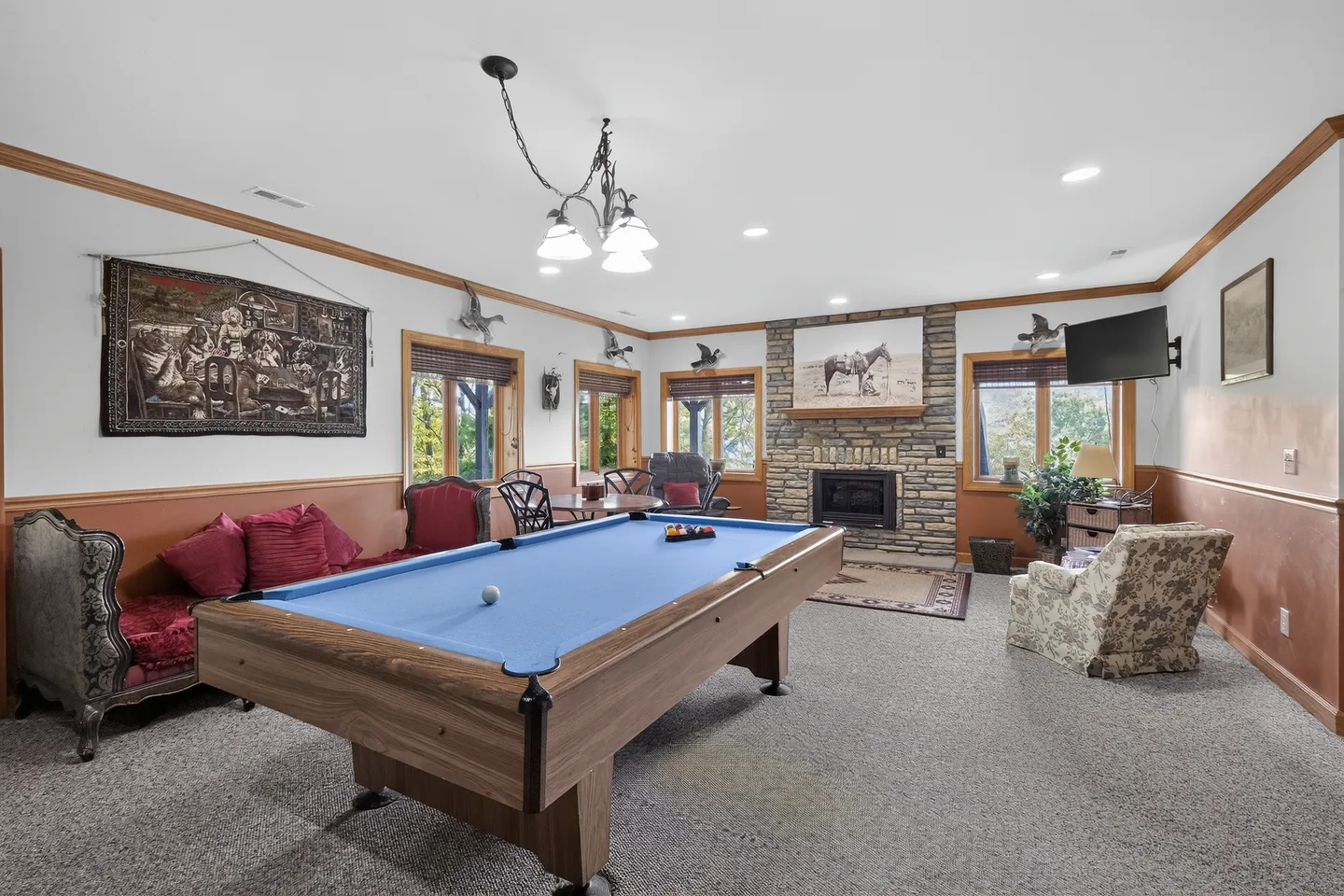Game room featuring a blue felt pool table, carpeted flooring, a stone fireplace, and various seating options.