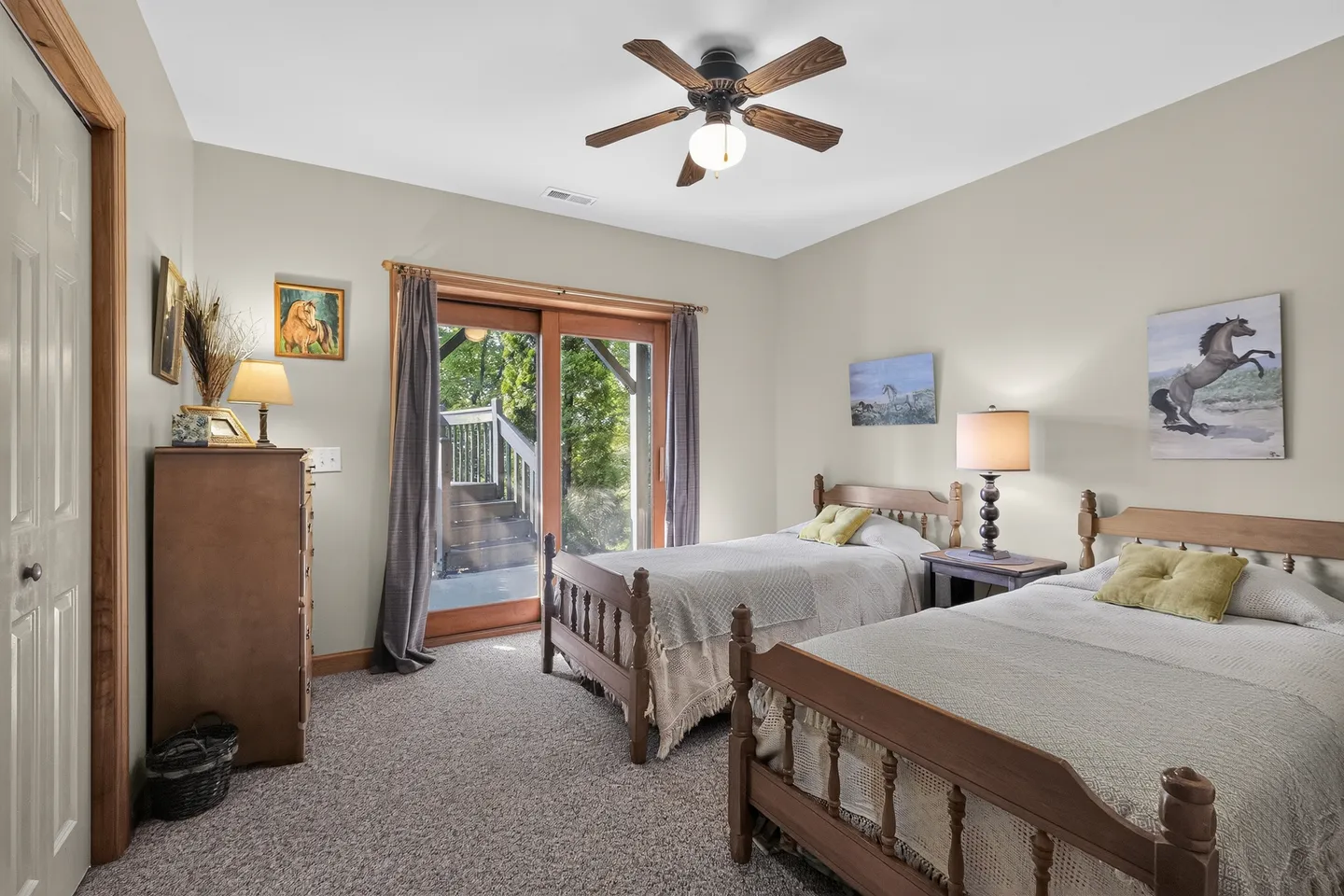Bedroom with two wooden twin beds, carpeting, a dresser, and sliding glass doors leading outside.