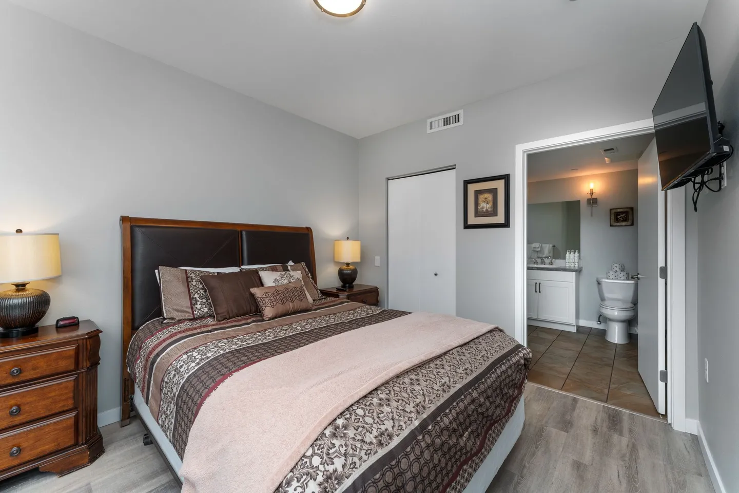 Bedroom with a wooden bed flanked by nightstands and an open doorway leading to an ensuite bathroom.