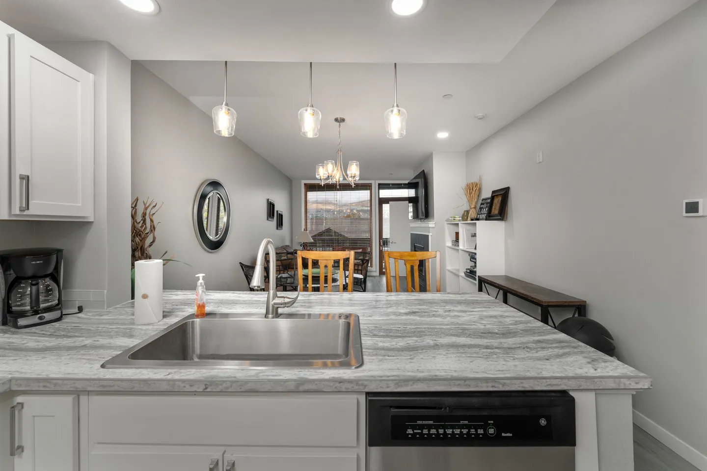 View from the kitchen island with stainless steel sink looking into the dining and living area.