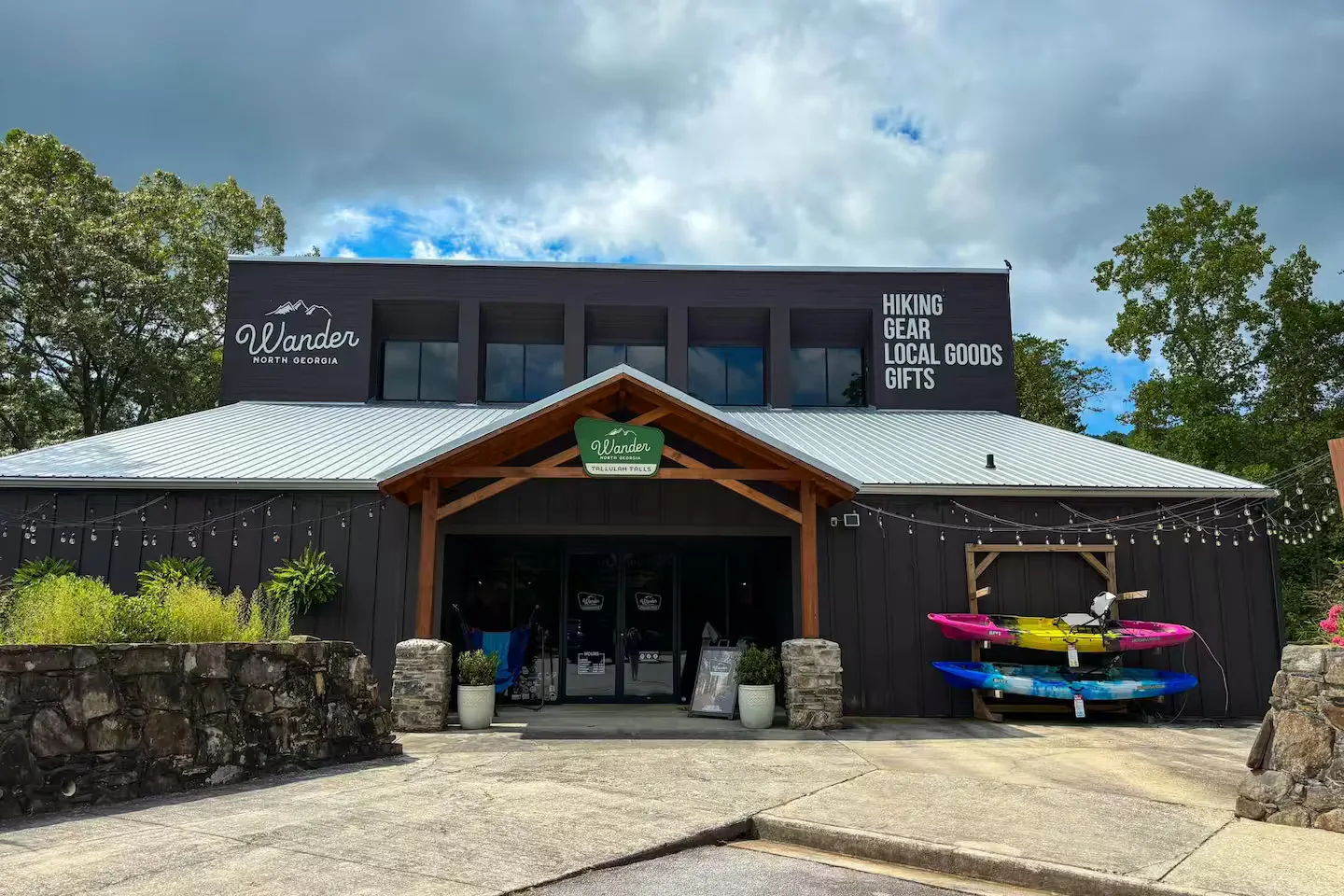 Exterior view of Wander North Georgia retail store with a covered entrance, kayak rack outside, and stone details.