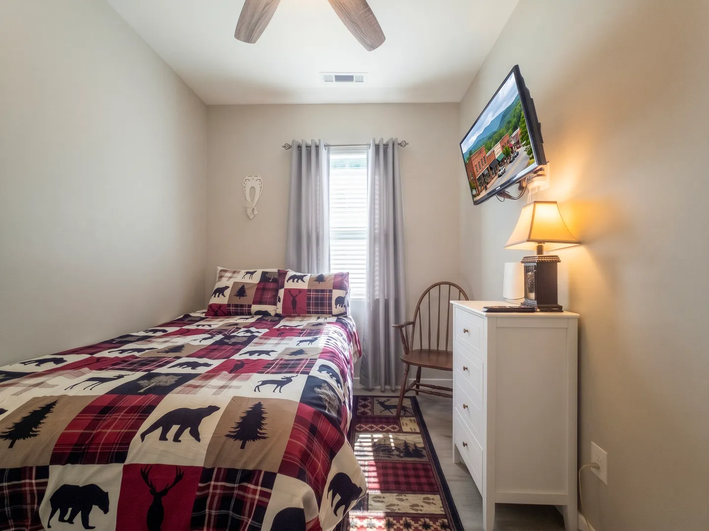 Bedroom with a single bed featuring wildlife-themed bedding, a white dresser, and a wall-mounted TV.