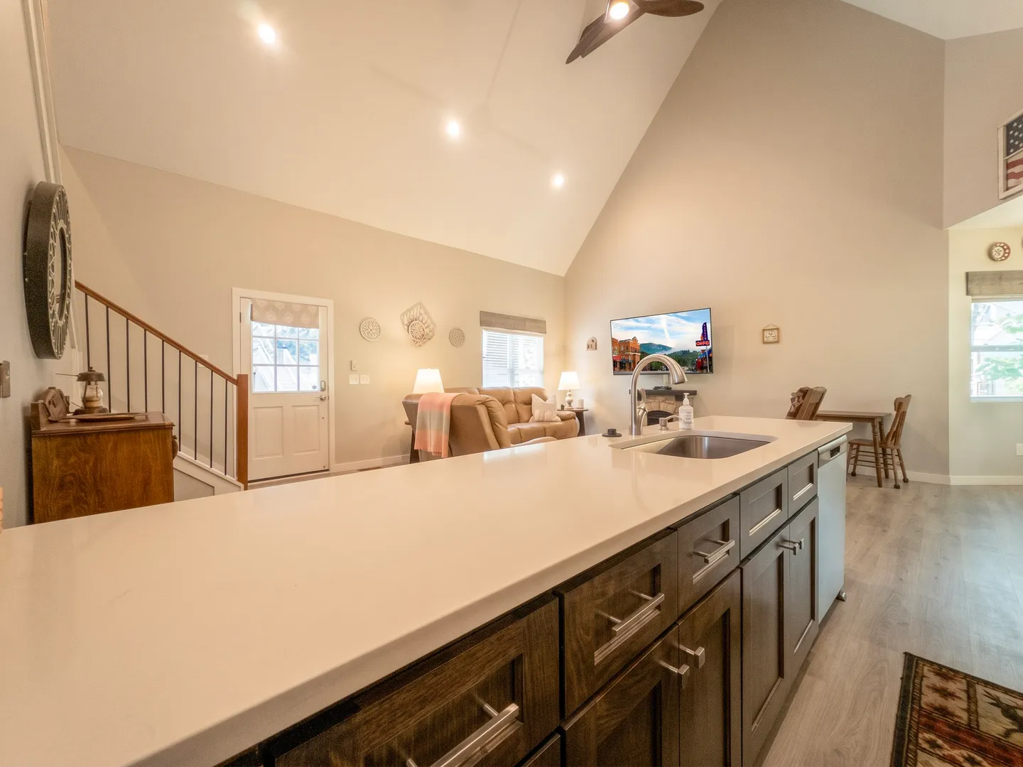 Open-concept living space viewed from a kitchen island with a built-in sink and dark wood cabinetry.
