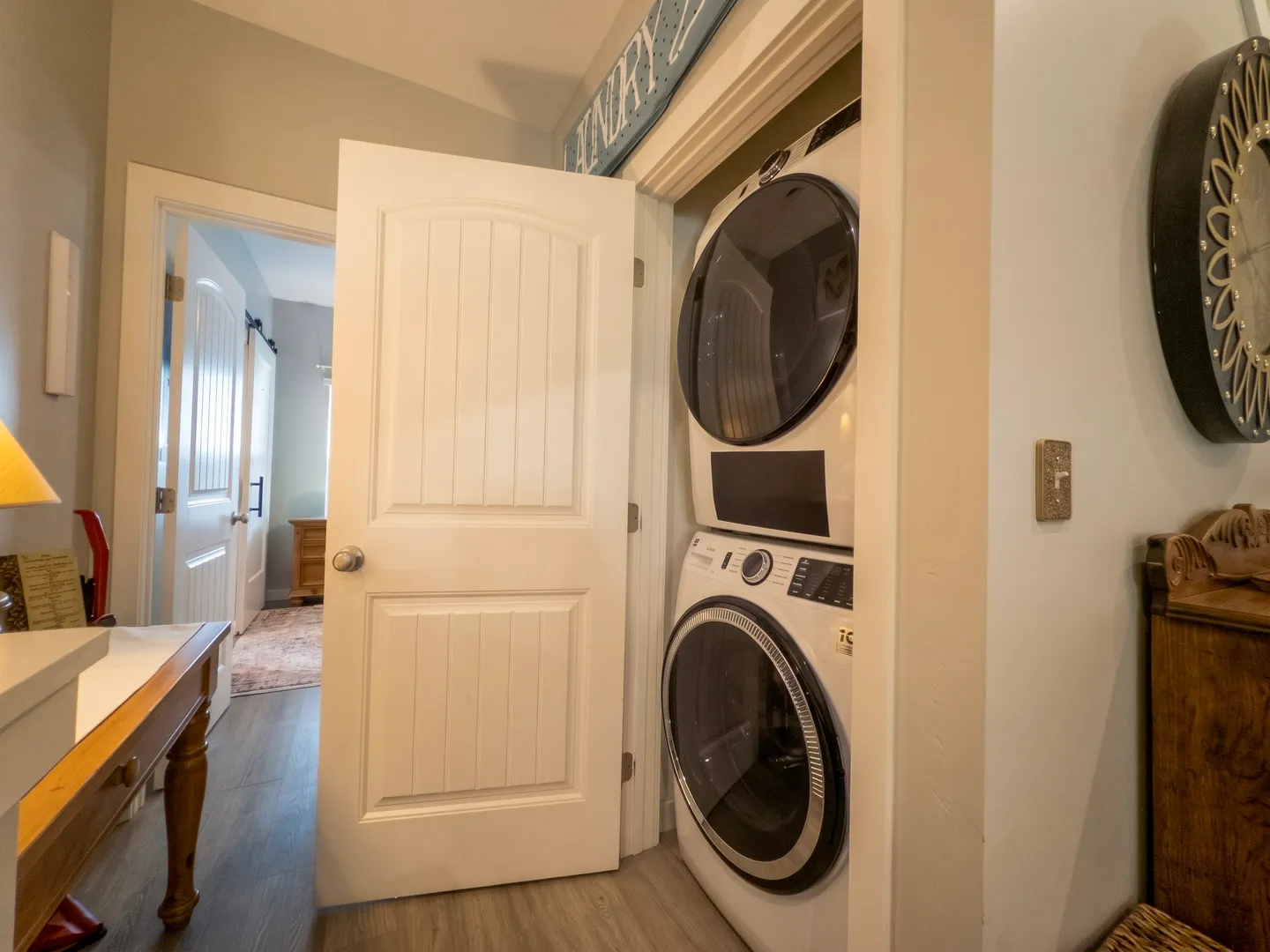 A stacked front-loading washer and dryer tucked into a hallway closet behind an open white door.