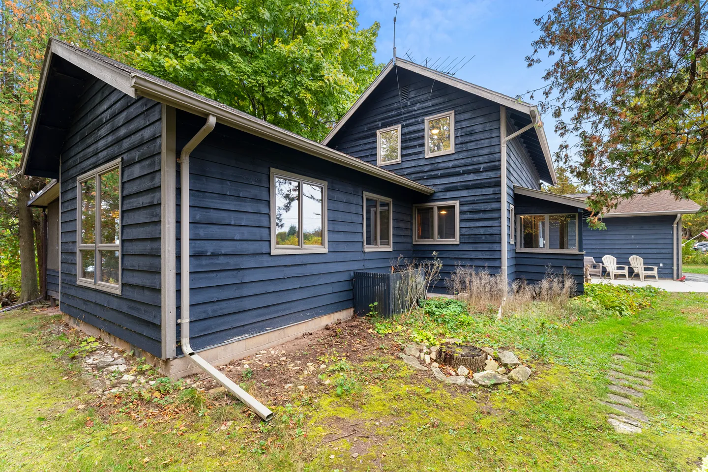 Exterior corner of a dark blue, two-story house with multiple windows and a grassy yard.