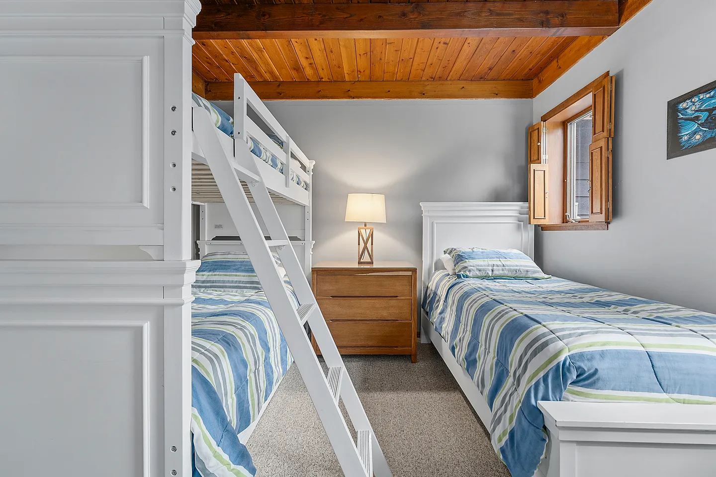 Bedroom featuring a white bunk bed, a twin bed, a wooden nightstand, and a wood-plank ceiling.