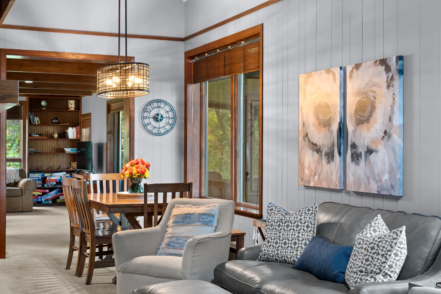 Living room with leather sofa, fabric armchair, owl artwork, and view into the adjacent dining area and den.