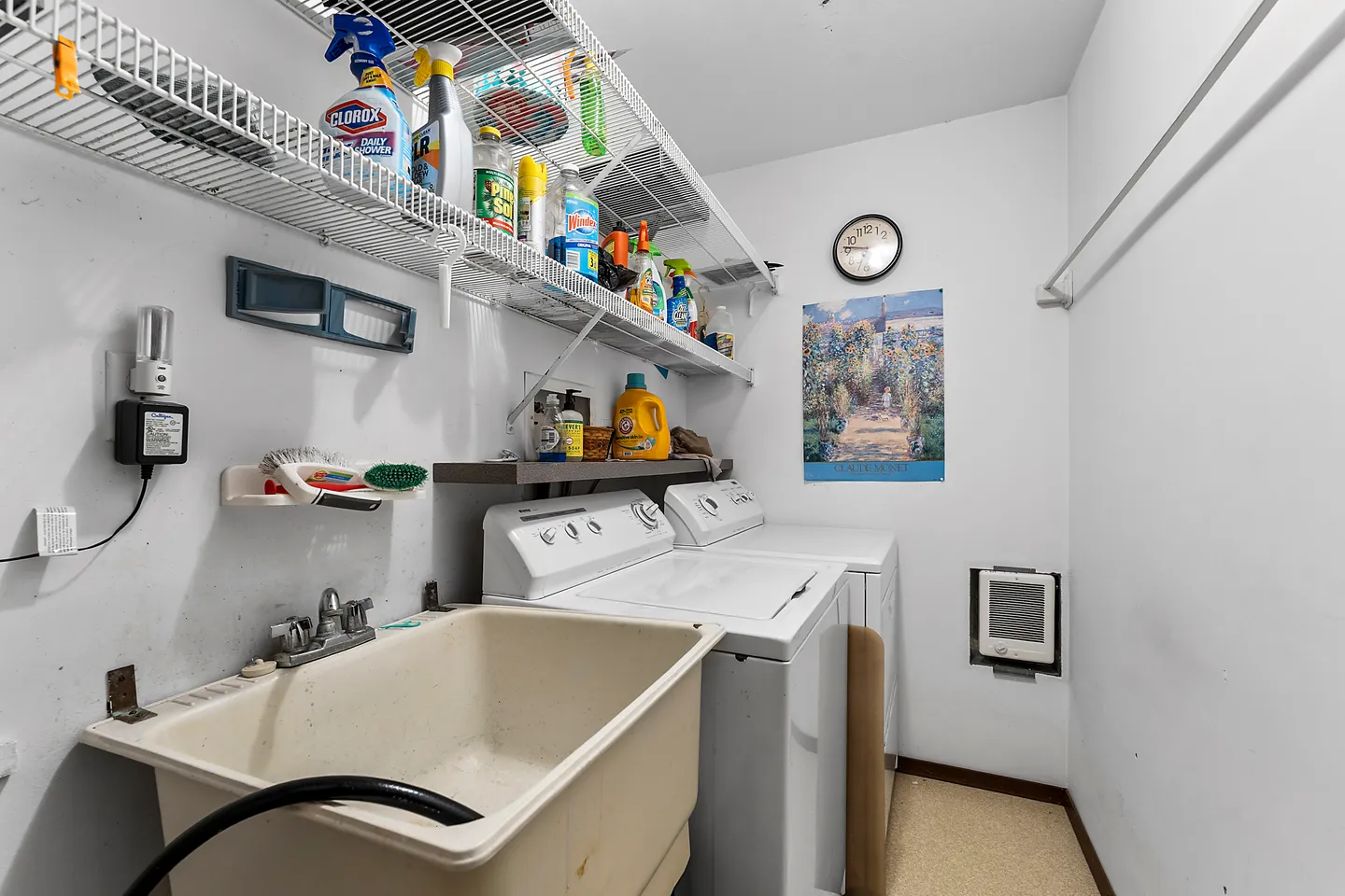Laundry room with a utility sink, washing machine, dryer, and wire shelving holding cleaning supplies.
