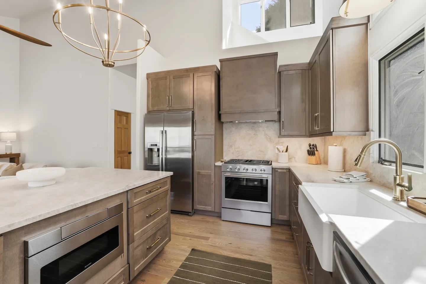 A kitchen with wood cabinets, stainless steel appliances, a farmhouse sink, and a center island.