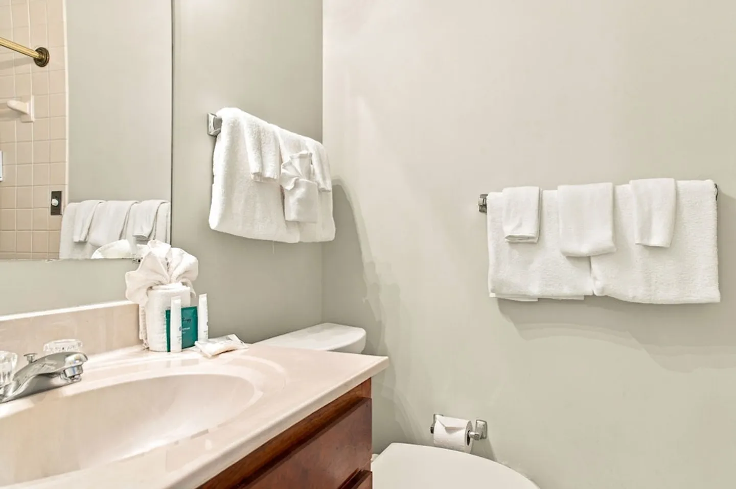 Bathroom vanity, toilet, and towel bars with folded white towels and guest toiletries.