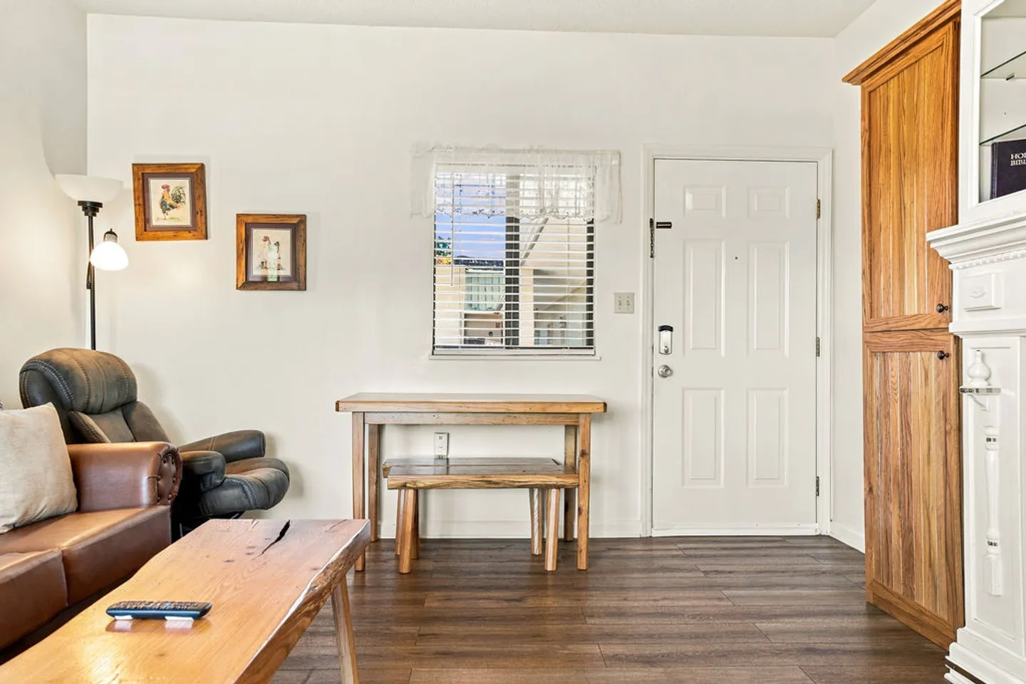Living room entryway with wood-look flooring, a front door, a small wooden table with a bench, and living room seating.