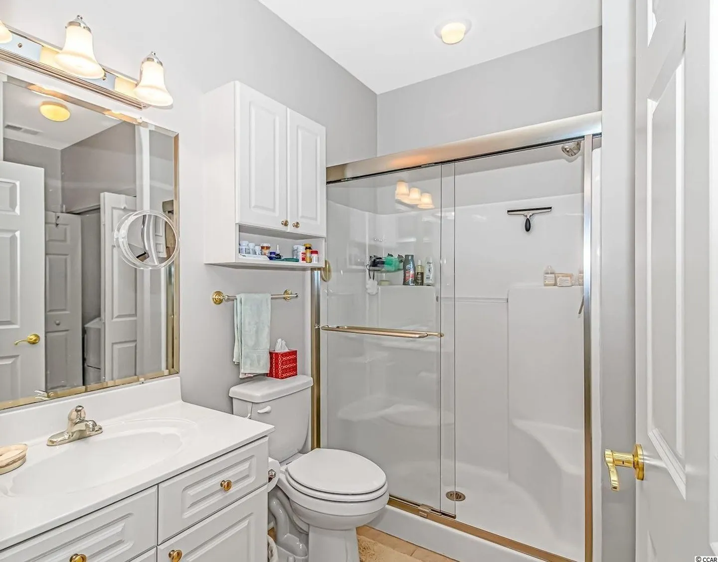 Bathroom with white vanity, toilet, and walk-in shower with sliding glass doors.