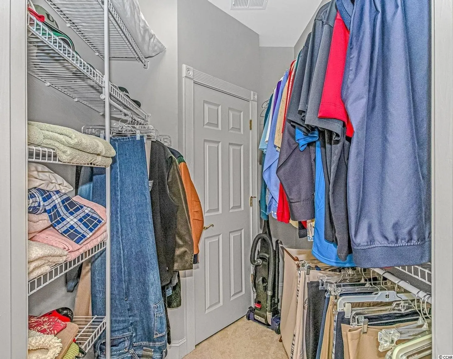 A walk-in closet with wire shelving and hanging racks filled with clothes and linens.